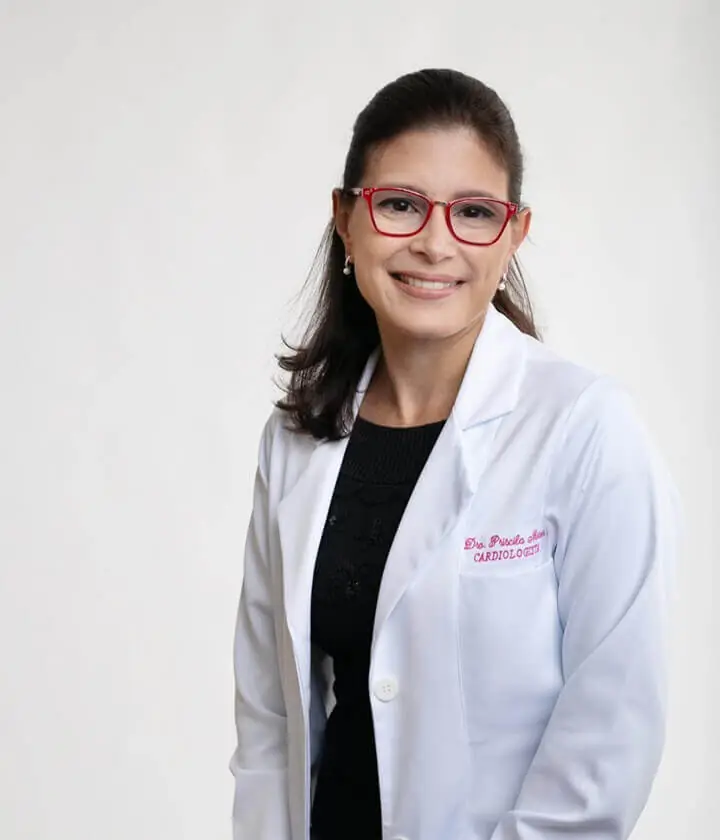 Dra. Priscila Nasser sorrindo, com jaleco branco e estetoscópio no pescoço, em consultório de cardiologia